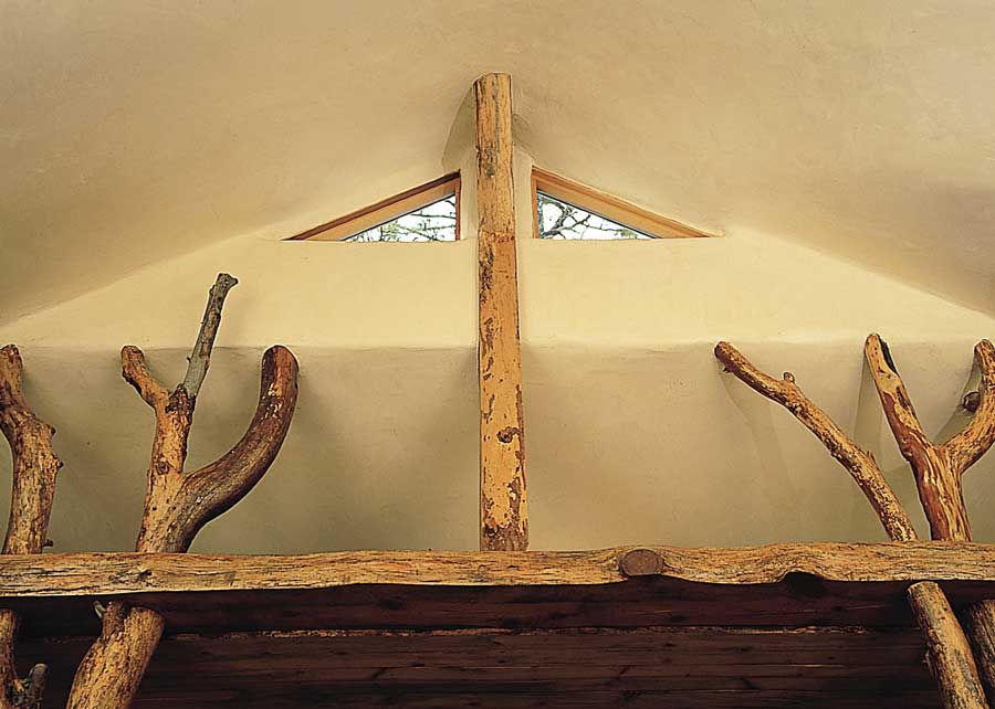 “I cut down two ponderosa pines purely for the sake of view and because I didn’t think they were very pretty,” Tom says. “I went through a lot of agonizing about it—‘what gives me the right to do this?’ But I cut them down. And then we were looking for a way of framing up the bedroom in a natural way and holding the roof up, and I thought, ‘What about those trees lying down out there?’ I hauled them in, and they became structural supports for the roof—and they’re gorgeous. They’re a headboard, and they’re bearing the whole roof. It was a good life lesson—what I had pushed away as ugly, later I had to bring back into my life and embrace as absolutely beautiful.”